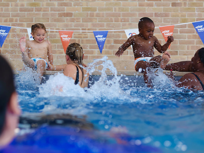 children splashing in pool with carers