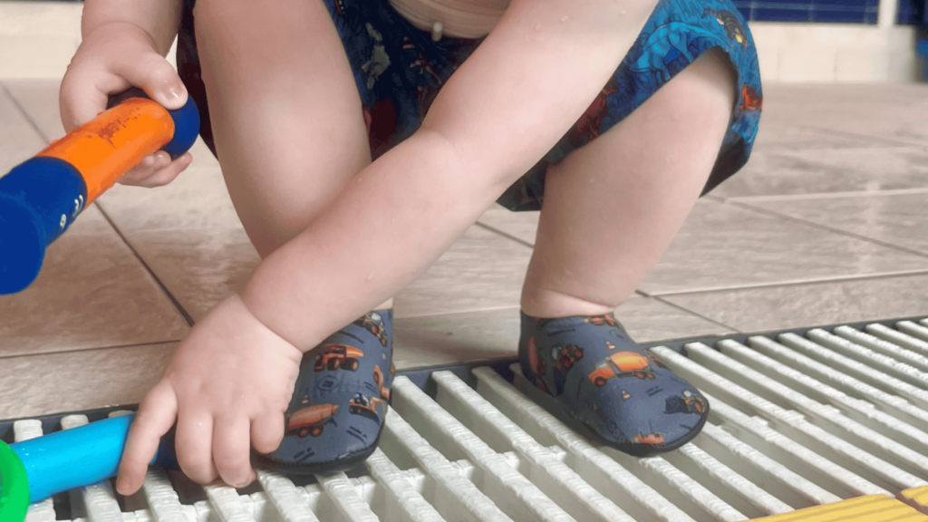 toddler crouching by poolside in slipfree shoes
