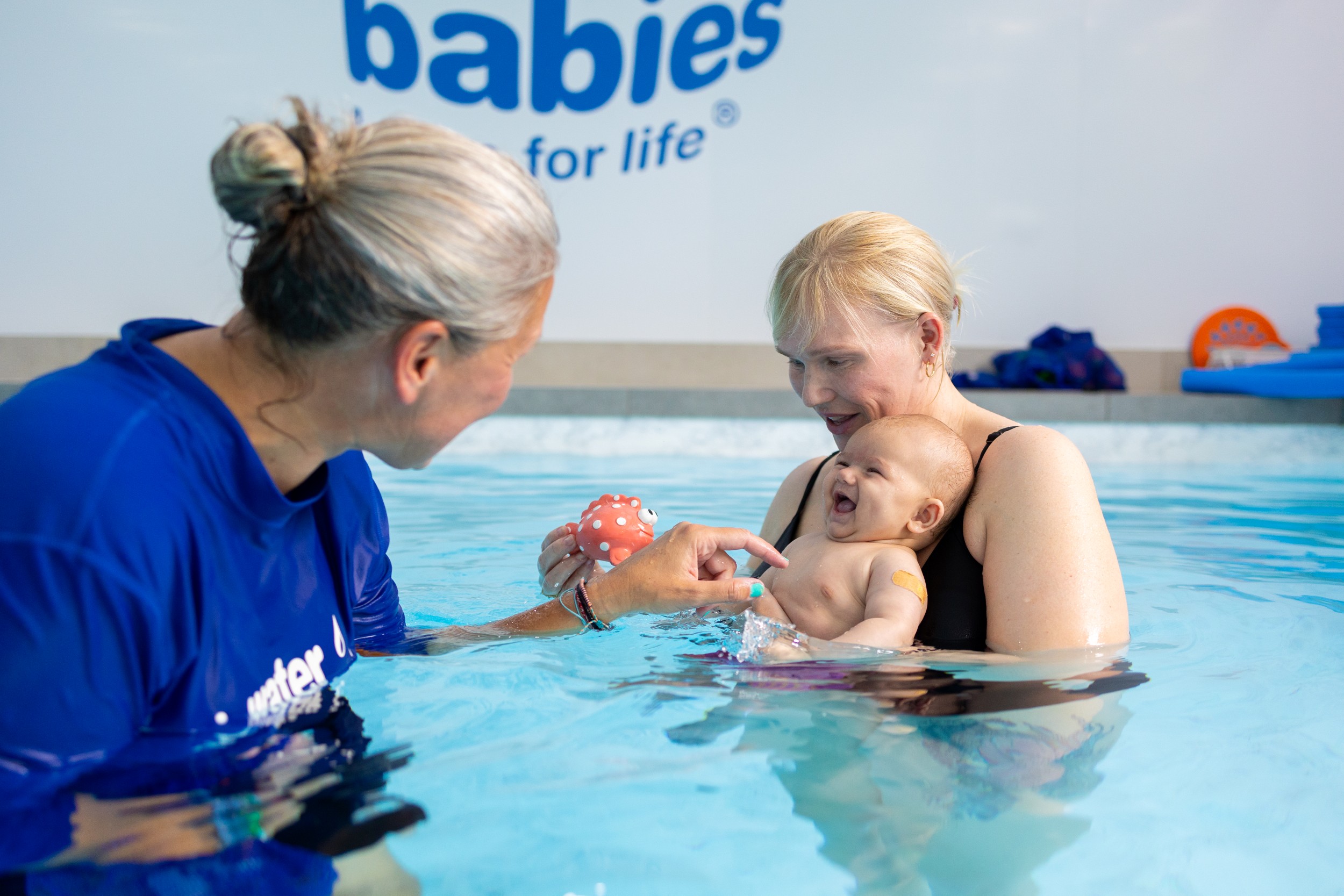 Teacher, baby and parent in a swimming pool